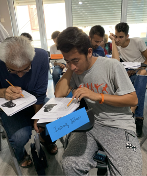 A group of students sitting in chairs writing on paper in a classroom.