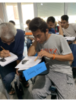 A group of students sitting in chairs writing on paper in a classroom.